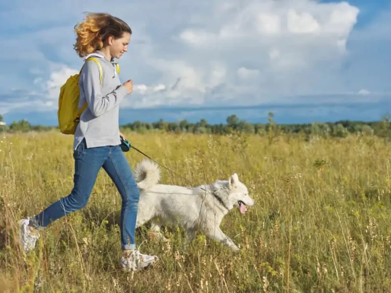 Vrouw wandelt actief met haar hond in een open veld