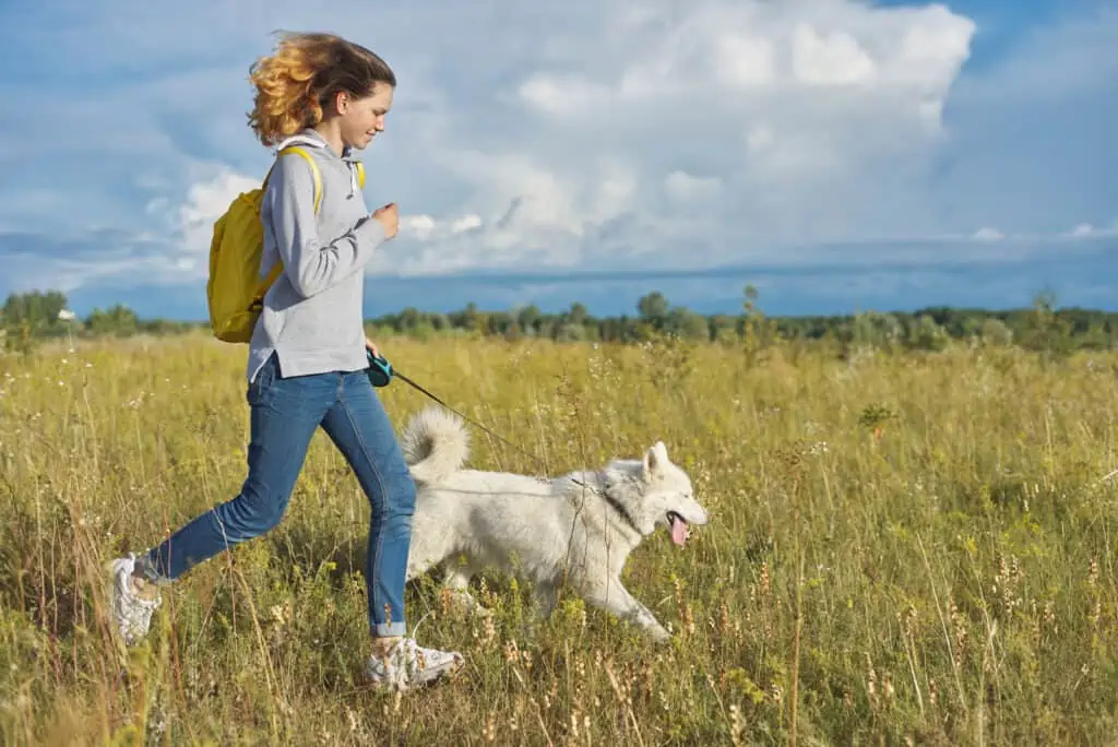 Vrouw wandelt actief met haar hond in een open veld
